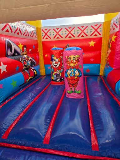 structure clown flers location orne A aire de jeu gonflable colorée avec des clowns et des motifs festifs.
